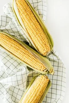 Raw ears of corn on blanket. Flat lay, top view vegetarian food concept. Stock Photos