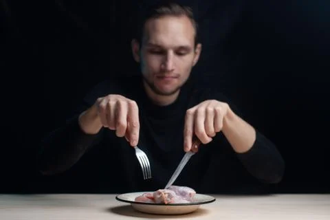 A raw-eating man eats raw chicken Stock Photos