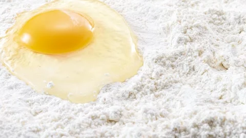 Raw egg cracked onto flour, baking preparation, zoom pan Stock Footage 337671037