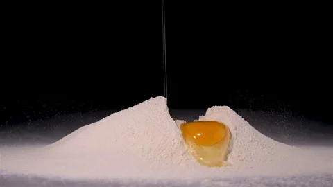 Raw egg falling in flour on black background Stock Footage 81180473