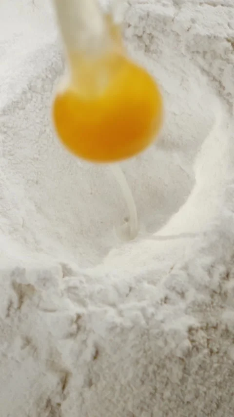 Raw egg falling into flour pile for baking preparation in professional kitc.. Stock Footage 337599093