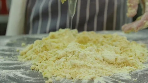 Raw egg falls on a pile of flour. Men's hands knead the dough on the kitchen Stock Footage 74715924