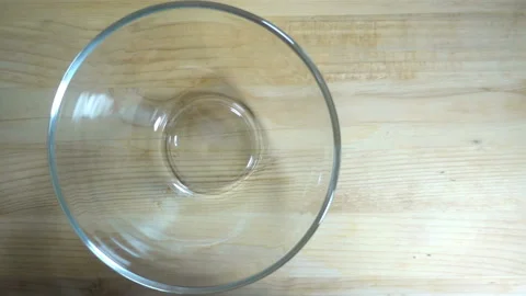 Raw egg falls in slow motion into a transparent bowl. Stock Footage 132643536