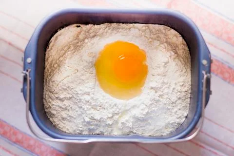 Raw egg on flour in the bread pan bowl. Baking homemade dough Stock Photos
