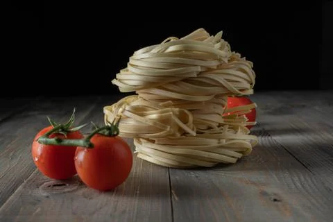 Raw egg noodles with tomatoes stacked on wood Stock Photos