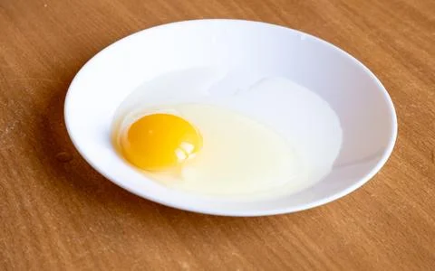 Raw egg in a plate on the table.Preparing breakfast. Stock Photos