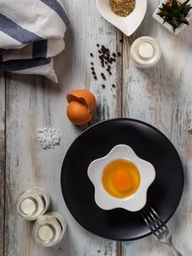 Raw egg on a rustic table top with kitchen utensils Stock Photos