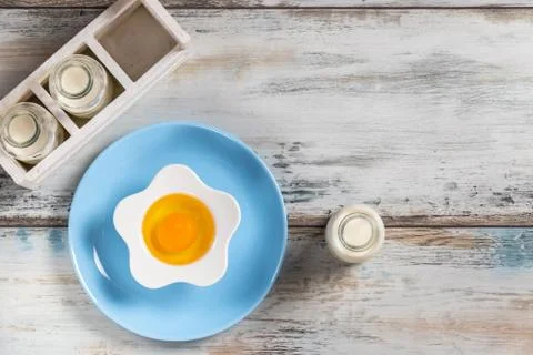 Raw egg on a rustic table top with kitchen utensils Foto stock