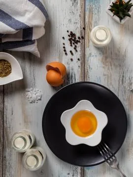 Raw egg on a rustic table top with kitchen utensils Foto stock
