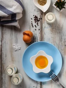 Raw egg on a rustic table top with kitchen utensils Stock Photos