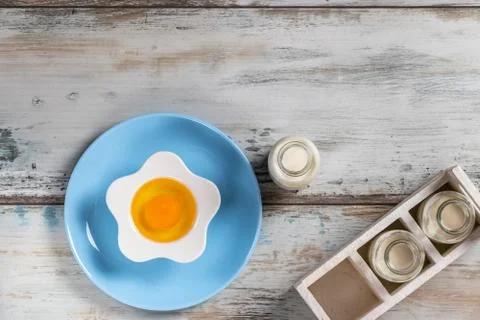 Raw egg on a rustic table top with kitchen utensils Foto stock