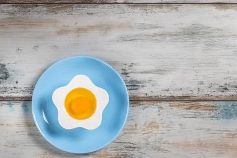 Raw egg on a rustic table top with kitchen utensils Foto stock
