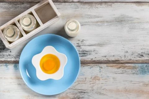 Raw egg on a rustic table top with kitchen utensils Stock Photos