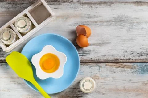 Raw egg on a rustic table top with kitchen utensils Foto stock