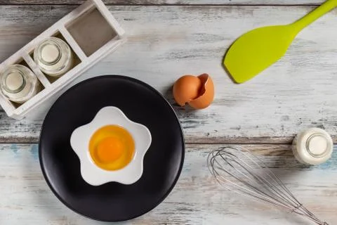 Raw egg on a rustic table top with kitchen utensils Stock Photos