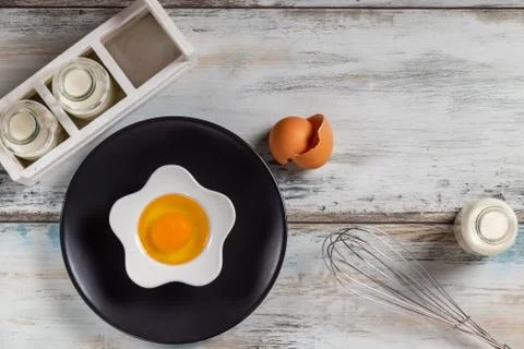 Raw egg on a rustic table top with kitchen utensils Foto stock