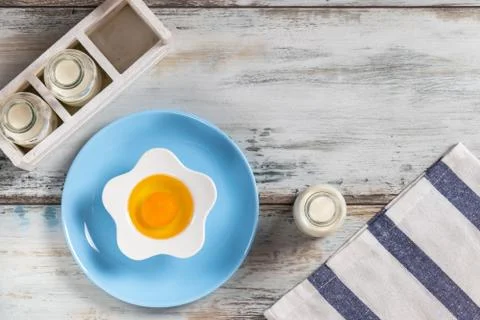 Raw egg on a rustic table top with kitchen utensils Foto stock