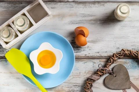 Raw egg on a rustic table top with kitchen utensils Stock Photos