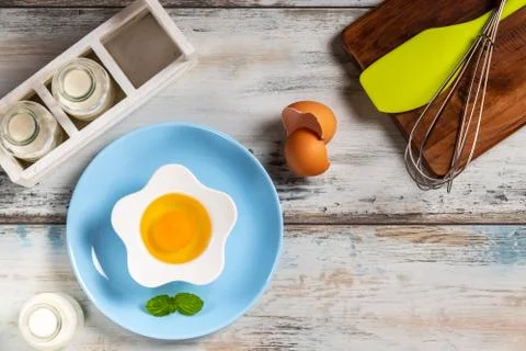 Raw egg on a rustic table top with kitchen utensils Foto stock