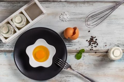 Raw egg on a rustic table top with kitchen utensils Foto stock