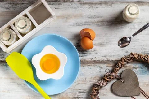 Raw egg on a rustic table top with kitchen utensils Stock Photos