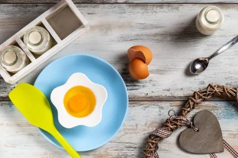 Raw egg on a rustic table top with kitchen utensils Foto stock