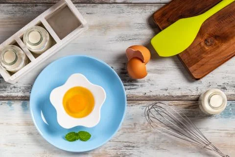 Raw egg on a rustic table top with kitchen utensils Foto stock