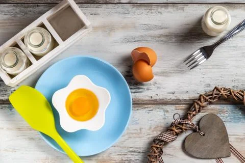 Raw egg on a rustic table top with kitchen utensils Stock Photos