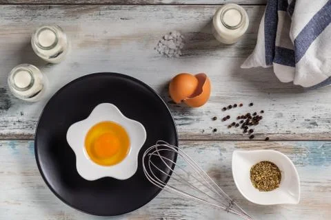 Raw egg on a rustic table top with kitchen utensils Stock Photos