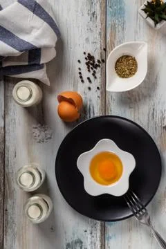 Raw egg on a rustic table top with kitchen utensils Stock Photos