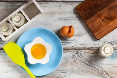 Raw egg on a rustic table top with kitchen utensils Foto stock