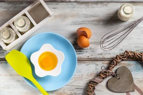 Raw egg on a rustic table top with kitchen utensils Stock Photos