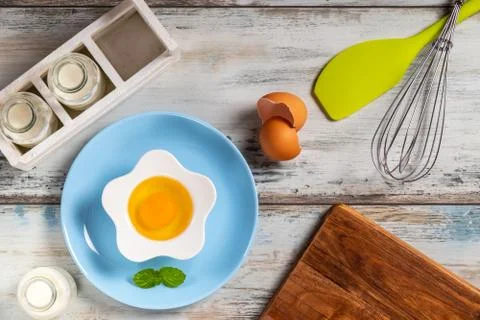 Raw egg on a rustic table top with kitchen utensils Foto stock