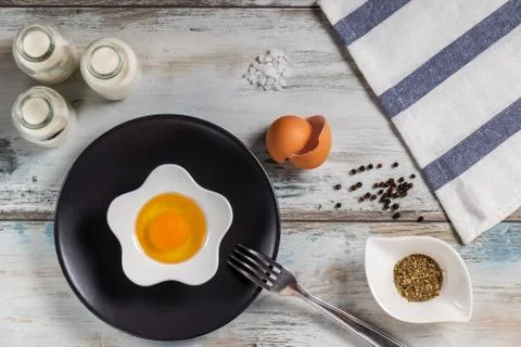 Raw egg on a rustic table top with kitchen utensils Foto stock
