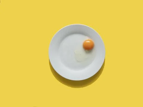 Raw egg on a white plate. View from above. Fresh egg with a bright yolk on .. Stock Photos