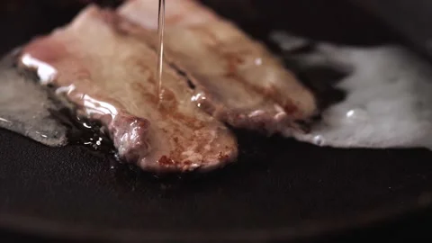 Raw egg, yolk falling on bacon, frying in a pan. Close-up Stock Footage 146334705