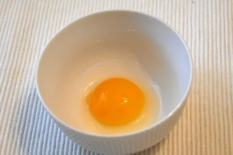 Raw egg yolk in a white bowl Stock-Fotos