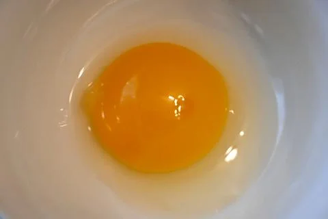Raw egg yolk in a white dish Stock Photos