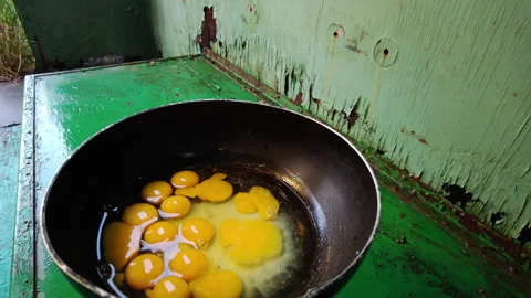 Raw egg yolks inside frying pan prepared for outdoor cooking camp meal Stock Footage 339591071