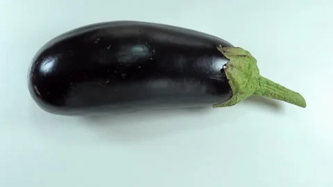 Raw eggplant vegetable rotates on a white Stock Footage 134727645