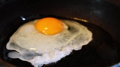 Raw eggs are broken into a hot cast-iron skillet 库存影片 308295766