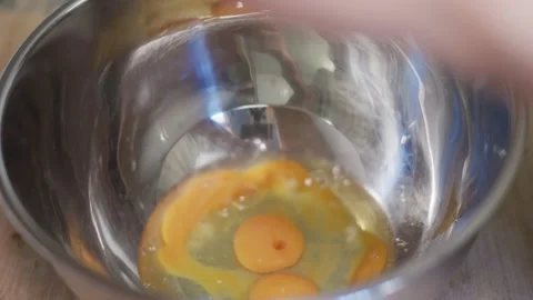 Raw eggs breaking into a shiny metal bowl Stock Footage 335869824