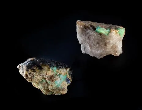 Raw emerald gemstone crystals inside feldspar rock with molybdenite, mica and Stock Photos