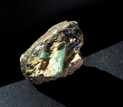 Raw emerald gemstone crystals inside feldspar rock with molybdenite, mica and Stock Photos