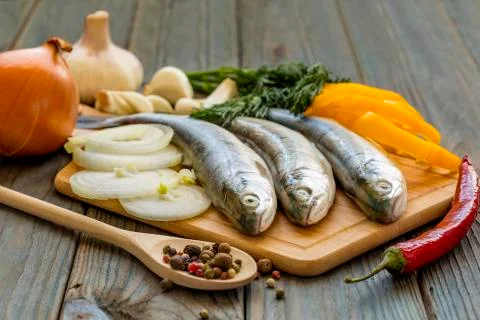 Raw fish on kitchen table with ingredients for cooking Stock Photos