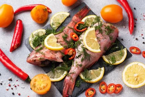 Raw fish perch without a head with lemon slices and dill greens and red hot.. Stock Photos