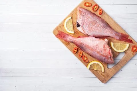Raw fish perch without a head with lemon slices and red hot chili peppers o.. Fotos Stock
