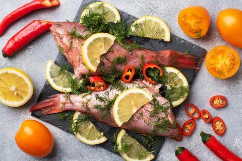 Raw fish perch without a head with lemon slices and dill greens and red hot.. Foto stock