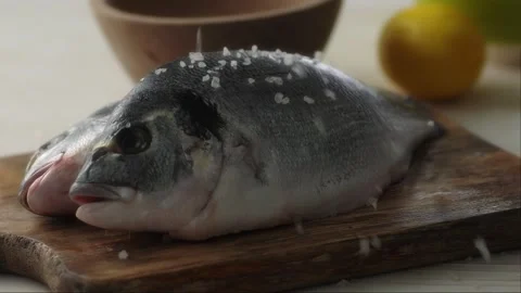 Raw Fish on a Wooden Board gets Sprinkled with Salt. Stock Footage 259177873
