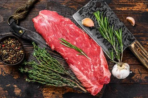 Raw flank beef meat steak on a cutting board with cleaver. Dark wooden Stock-Fotos